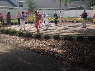 Here's an alt tag for the image: `Seniors walking a labyrinth outdoors.`