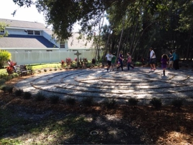 Here's an alt tag for the image: Children walking a garden labyrinth.