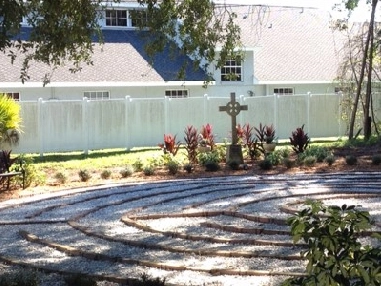 Here's an alt tag for the image: Peaceful garden labyrinth with Celtic cross.