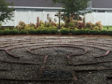 Here's an alt tag for the image: Serene garden labyrinth with Celtic cross.