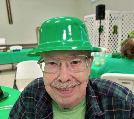 A man wearing green hat and glasses at a party.