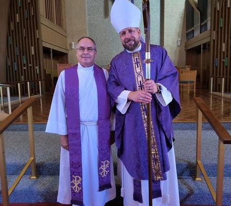 Two men in purple robes and hats standing next to each other.