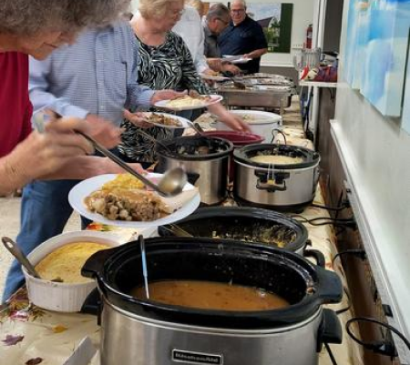 A group of people standing around a table with food.